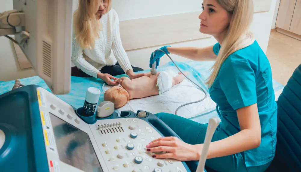 medic efectueaza o ecografie de sold la bebelus